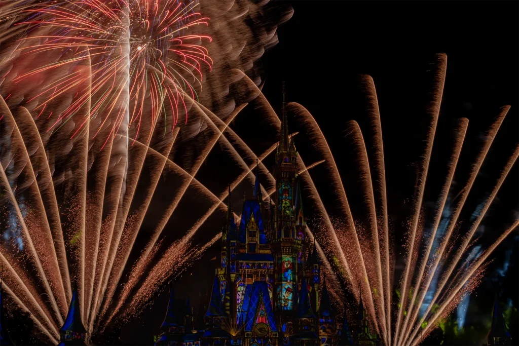 Golden sweeping fireworks frame the illuminated castle beneath a large burst in the night sky.
